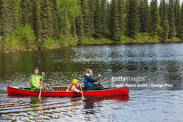 family in red canoe on byers lake with green tree covered shoreline, denali state park - family red canoe stock pictures, royalty-free photos & images