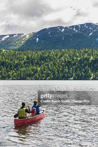 a couple and young girl in a red canoe on byers lake with green forested shoreline and foothills in the background, denali state park - family red canoe stock pictures, royalty-free photos & images