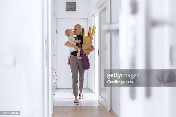 giovane madre entra in casa, con il suo neonato e la borsa della spesa - carrying groceries foto e immagini stock