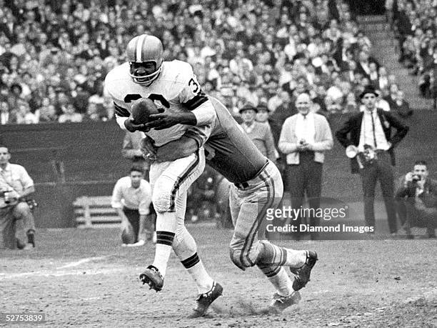 Runningback Jim Brown of the Cleveland Browns, tries to shake a tackle during a game on November 15, 1964 against the Detroit Lions at Municipal...