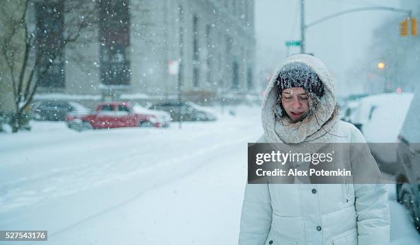teenager girl walks under snowfall at the street in manhattan - winter storm stock pictures, royalty-free photos & images