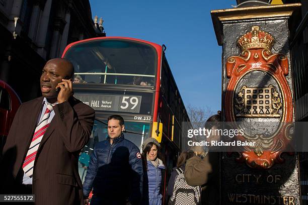 Seen from a low angle, late afternoon pedestrians walk into bright sunlight on the Strand in central London. Londoners make their way into the...