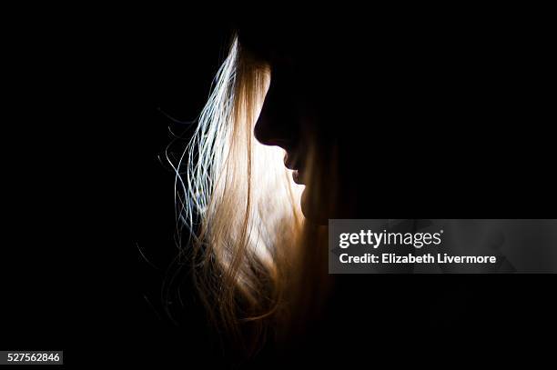 silhouette of woman's face at night - dark background light stock-fotos und bilder