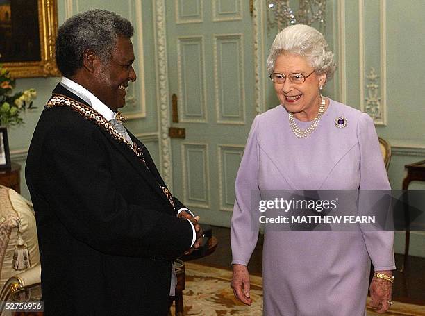 Queen Elizabeth II smiles after investing Governer-General of the Solomon Islands Sir Nathaniel Waena as a Knight Grand Cross of the Order of St...