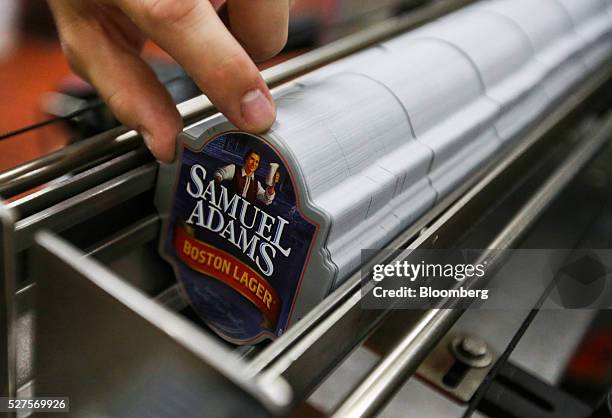 An employee places bottle stickers for Samuel Adams Boston Lager into a dispensing tray on the production line at the Shepherd Neame Plc brewery in...