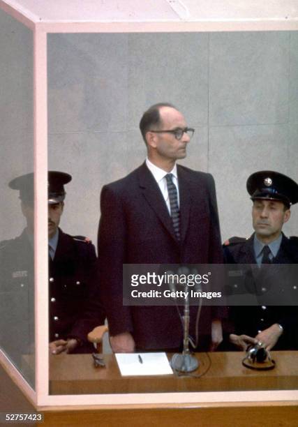 Nazi war criminal Adolph Eichmann stands in a protective glass booth flanked by Israeli police during his trial April 21, 1961 in Jerusalem. The...
