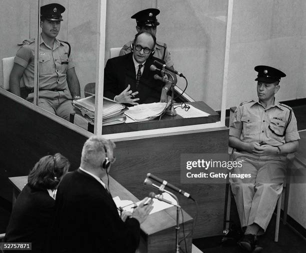 Nazi war criminal Adolph Eichmann stands in a protective glass booth flanked by Israeli police during his trial June 22, 1961 in Jerusalem. The...