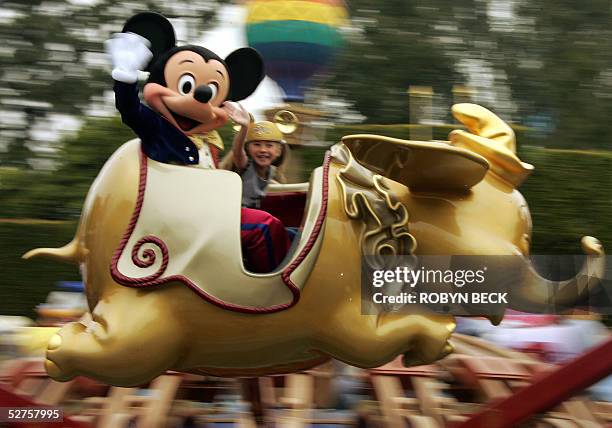 Mickey Mouse rides on a golden Dumbo with Caroline Sunshine age nine, on the Disney 50th anniversary press preview day at Disneyland in Anaheim, CA,...