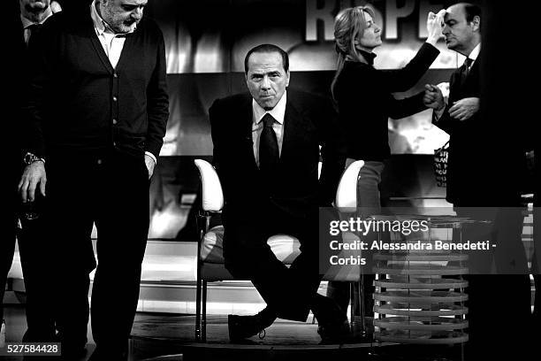 Italian Prime Minister Silvio Berlusconi adjusts his microphone before taking part in a political talk show at the Italian TV channel RAI's broadcast...