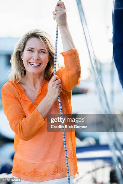 portrait of mature attractive woman on sailboat - tossing hair facing camera woman outdoors stock-fotos und bilder