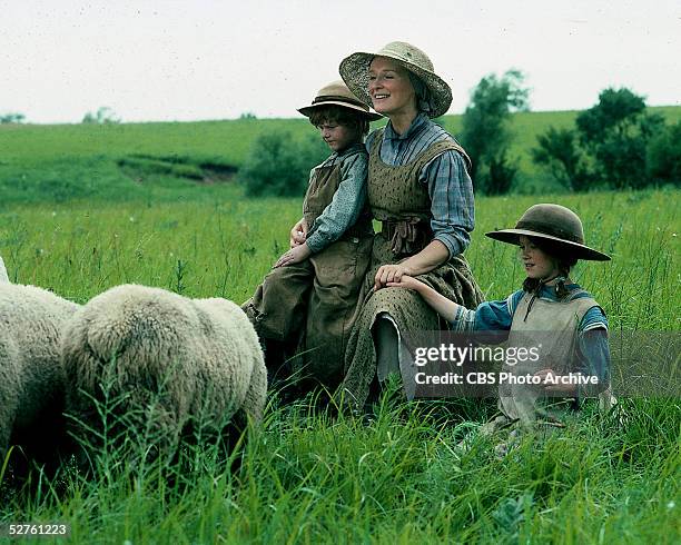 American actress Glen Close sits in a field with child actors Christopher Bell and Lexi Randall in a scene from the television movie 'Sarah Plain and...
