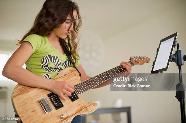 girl (10-12) playing guitar next to tablet pc - gitaarplectrum stockfoto's en -beelden