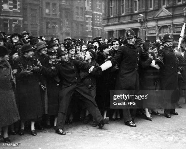 Three English policemen struggle to hold back the crowd at the wedding of the Bernard Marmaduke Fitzalan-Howard, 16th Duke of Norfolk to the...