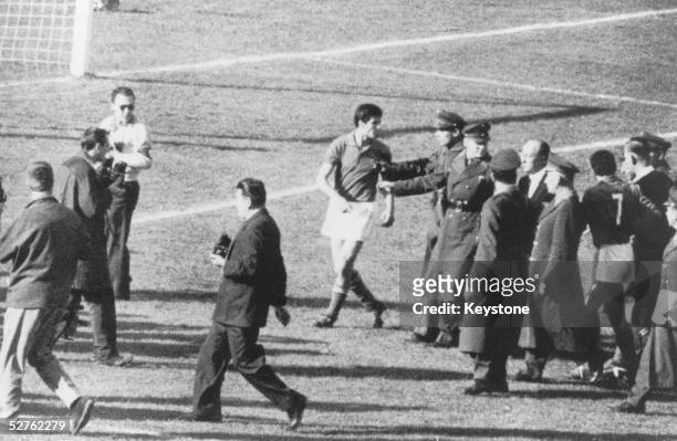 Police officers restrain Italian player Salvatore after one of the many violent altercations, which marred the match between Italy and Chile in the...