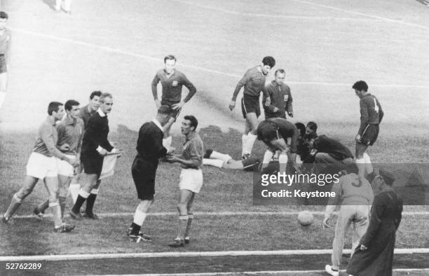 English referee Ken Aston sends off Italian player Mario David, while an injured Chilean lies on the ground, during the match between Italy and Chile...
