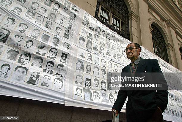 Una persona pasa frente a fotos de desaparecidos durante la dictadura de Augusto Pinochet colgadas frente al palacio de Tribunales, en Santiago el 05...