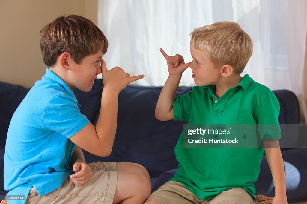 Boys with hearing impairments signing silly in American sign language on their couch