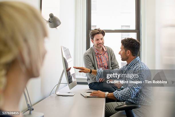 three business colleagues in an office, two talking and one standing by the door.  - ostracized stock pictures, royalty-free photos & images