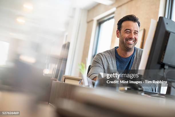 office life. a man seated at a desk using a computer. - wellbeing at work stock pictures, royalty-free photos & images