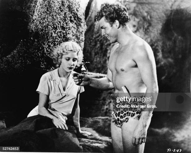 American actor Buster Crabbe , as Tarzan and wearing a loin cloth, communicates with actress Julie Bishop , as Jane, in a scene from the film 'Tarzan...