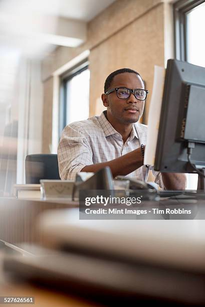 office life. a man seated at a desk using a computer. - ragazzo new york foto e immagini stock