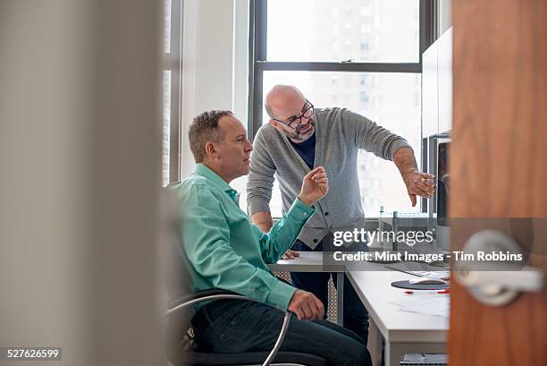 two men in an office looking at a computer screen. - office doorway stock pictures, royalty-free photos & images