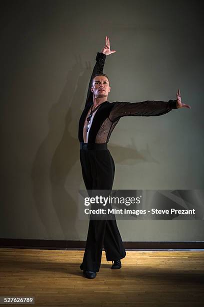 dancer in dance studio. a man with one arm stretched out and one arm raised. - danse de salon photos et images de collection