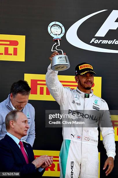 Lewis Hamilton of Great Britain and Mercedes GP raises his trophy for his second placed finish on the podium, Russian President Vladimir Putin...