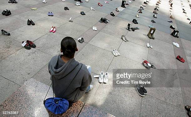 Woman sits amongst some of 1,200 shoes, representing the number of people who die each day from tobacco use and exposure to secondhand smoke,...