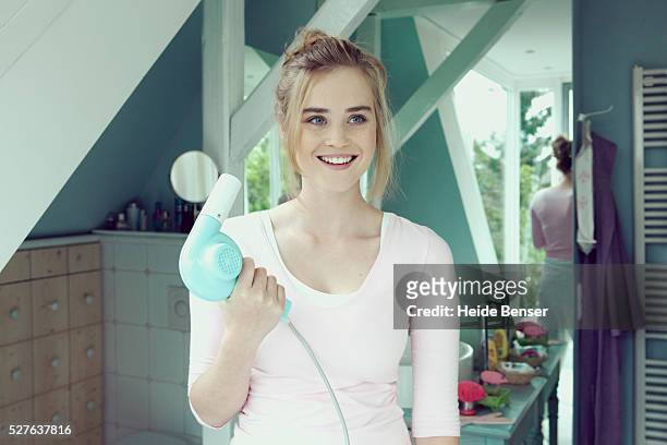 young woman in bathroom holding hairdryer - secador de cabelo - fotografias e filmes do acervo
