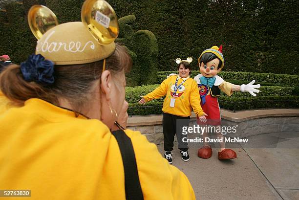 Eleven-year-old Shawn Leu of Portland, Oregon, poses for a snapshot by his mother Debaree, with golden 50th anniversary commemorative mouse ears,...
