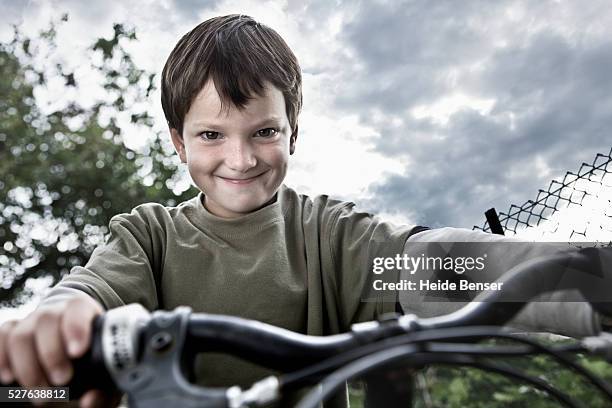 portrait of boy (7-9) on bike making face - inmaduro fotografías e imágenes de stock