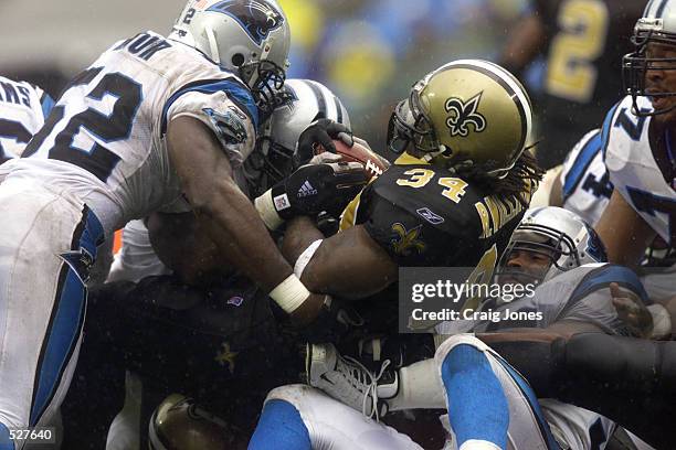 Ricky Williams of the New Orleans Saints gets tackled by Kris Jenkins and Kory Minor of the Carolina Panthers during the game at Ericsson Stadium in...