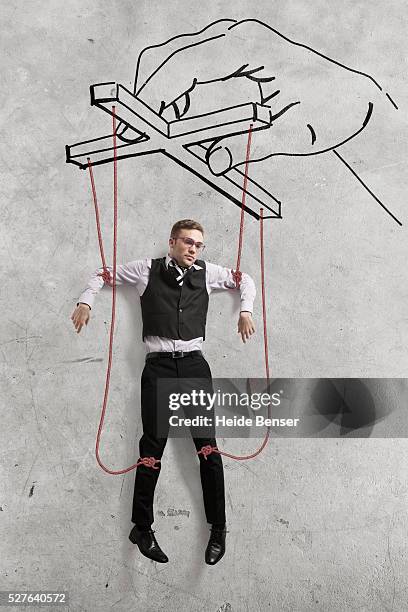 businessman dangling on threads - puppeteer photos et images de collection