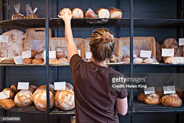 waitress selecting loaf of bread - bakery imagens e fotografias de stock