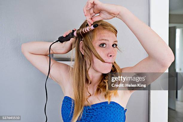 teenage girl (16-17) curling her hair - fer à friser photos et images de collection