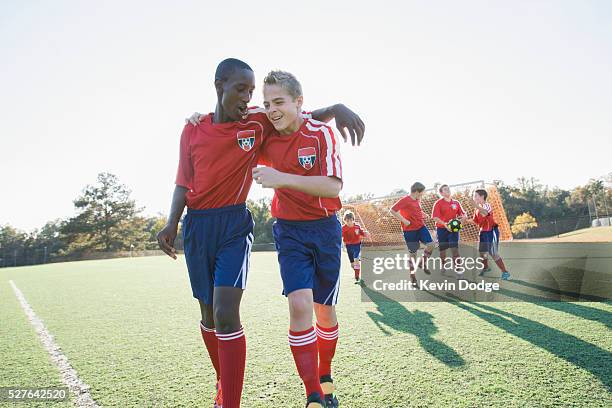 happy teammates (8-9) walking off soccer field after game - children soccer team stock pictures, royalty-free photos & images