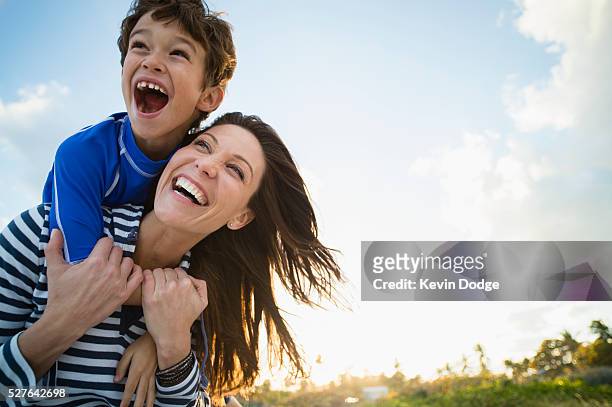 woman with son (10-12) playing at beach - figlio maschio foto e immagini stock