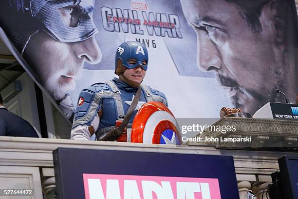 Man wearing a Captain America costume poses as Chris Evans and Jeremy Renner ring NYSE opening bell at New York Stock Exchange on May 3, 2016 in New...