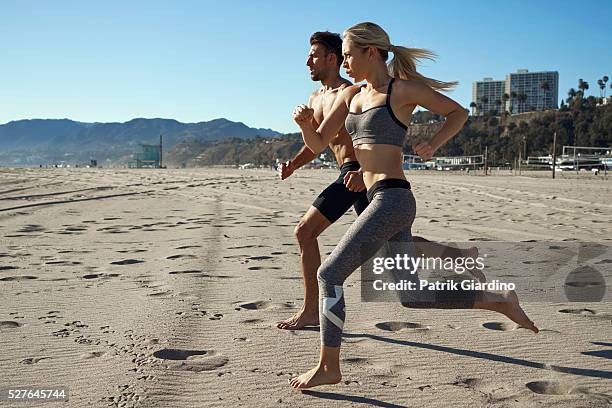 young woman and man running on beach - barefoot couples stock pictures, royalty-free photos & images