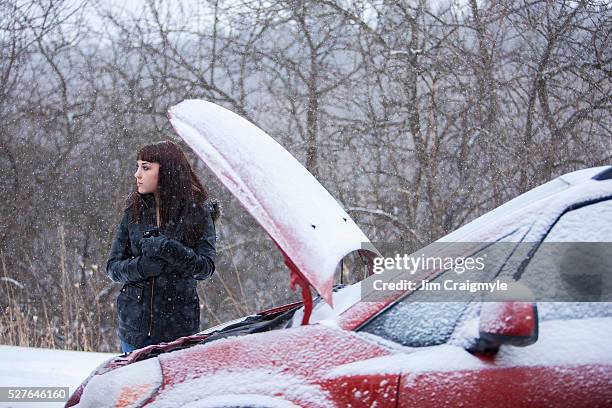 woman standing beside broken car in winter - winter panne auto stock-fotos und bilder