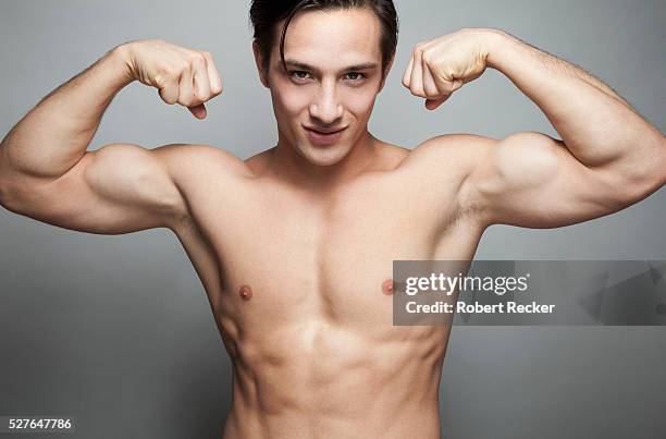 young guy flexing muscles - oberkörperaufnahme stock-fotos und bilder