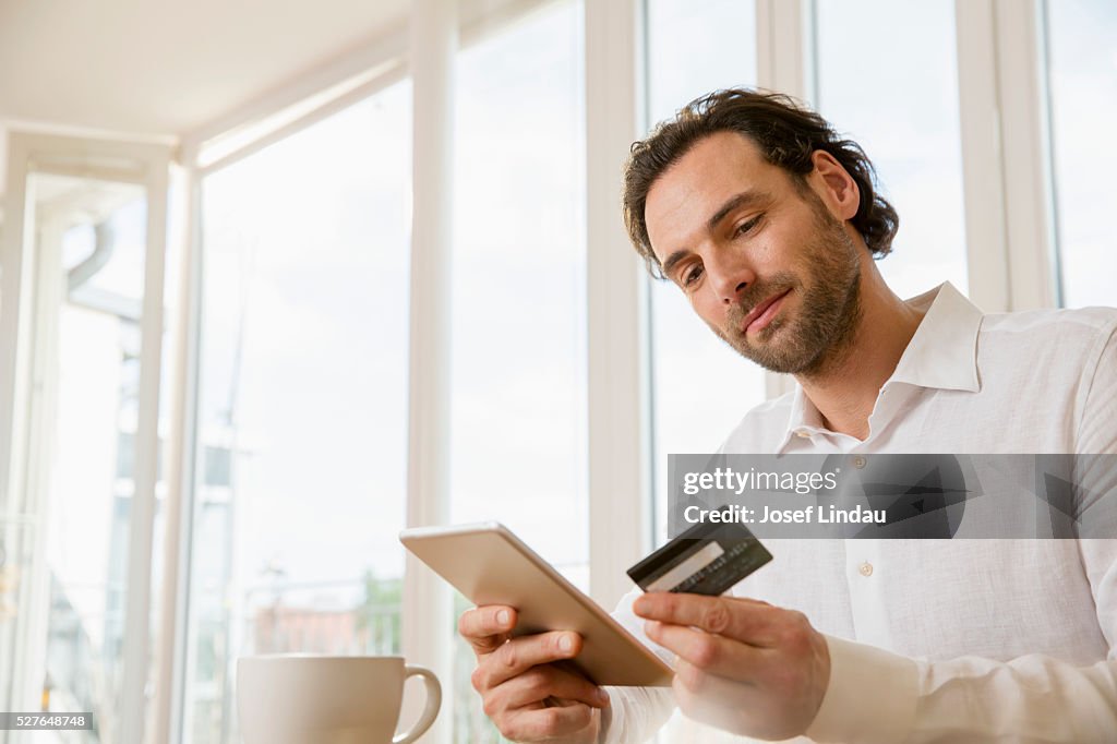 Portrait of man using digital tablet and credit card in office