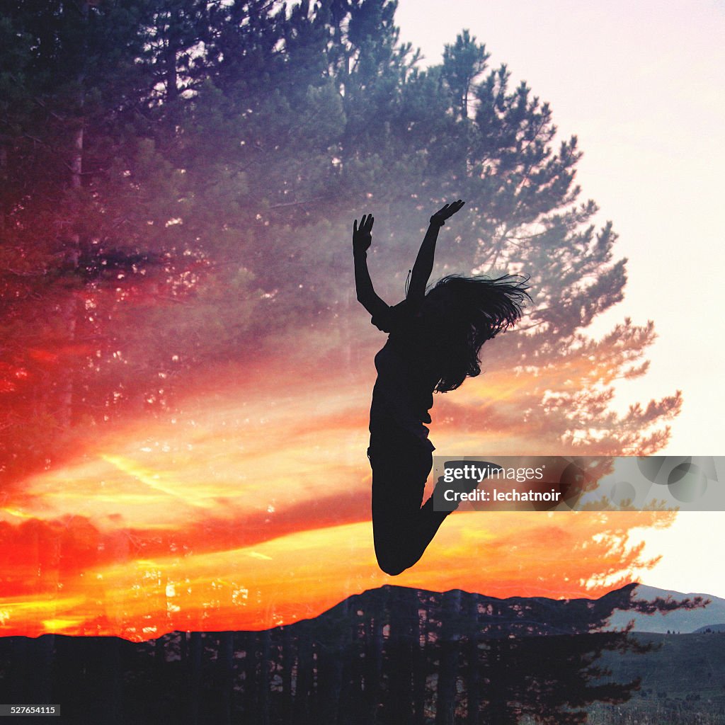 Double exposure silhouette of a girl jumping against sunset