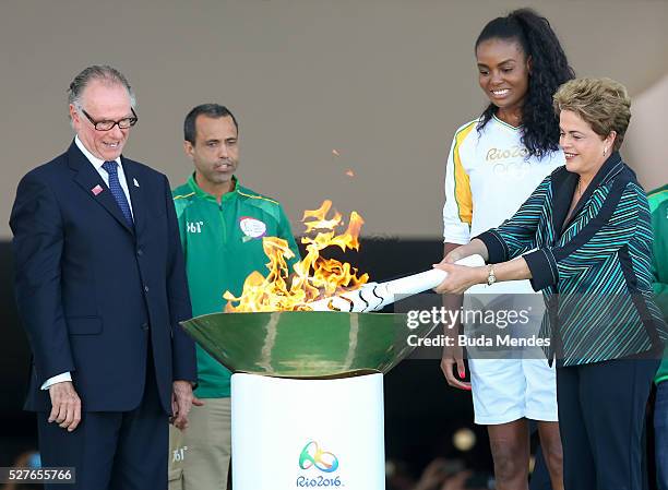 Dilma Rousseff, President of Brazil, lights the Olympic torch with Brazilian Olympic Committee Carlos Nuzman and first torch bearer, volleyball...