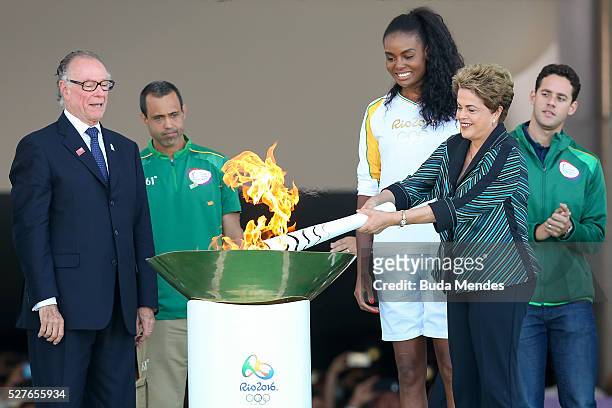 Dilma Rousseff, President of Brazil, lights the Olympic torch with Brazilian Olympic Committee Carlos Nuzman and first torch bearer, volleyball...