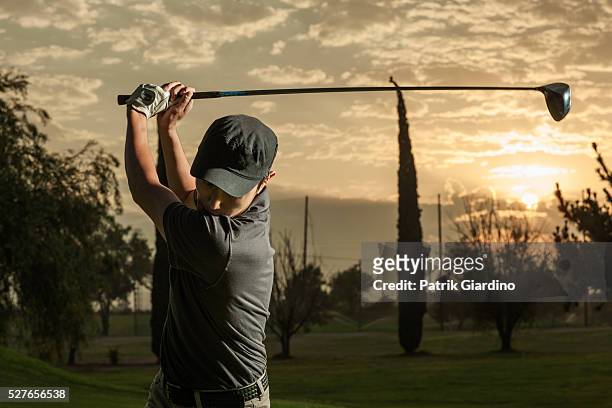 young man playing golf at sunset - golfschwung stock-fotos und bilder