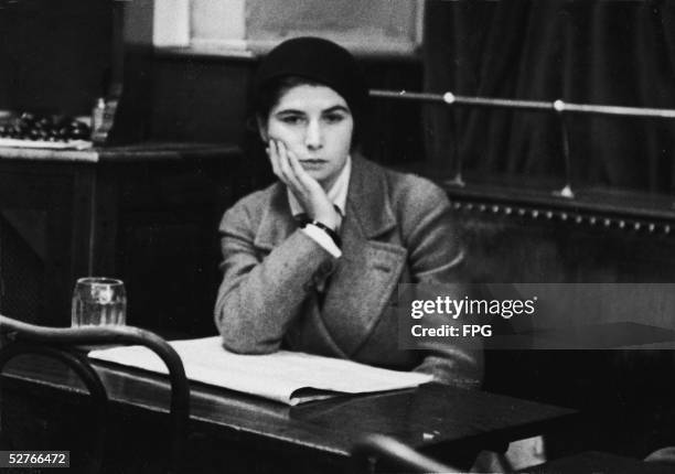 Young French bohemian woman sits at a table and rests her head on her hand at the fashionable artists' hangout Cafe de la Rotonde, Montparnasse,...