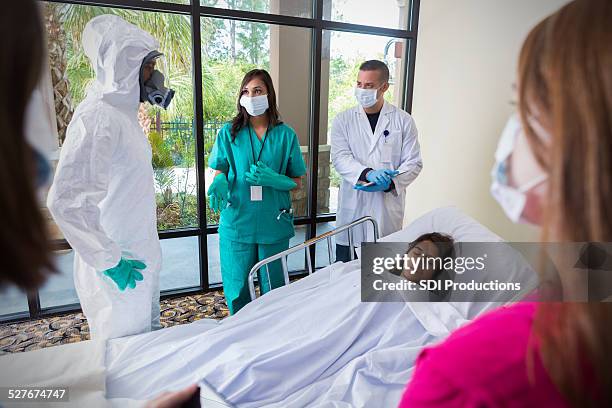 hospital staff wearing masks and protective gear around infected patient - ebola stock pictures, royalty-free photos & images