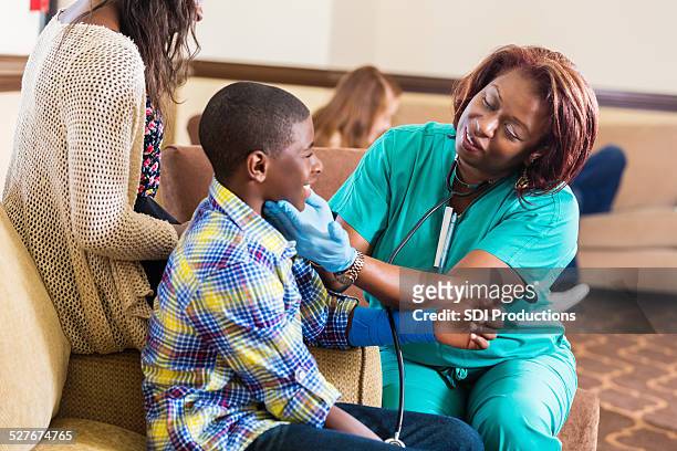 krankenschwester überprüfung auf preteen boy im krankenhaus wartet zimmer - doctor patient cast stock-fotos und bilder